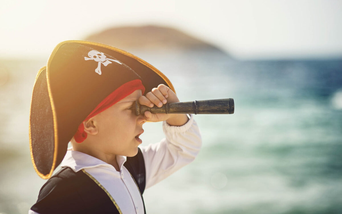 child in pirate costume looking through telescope